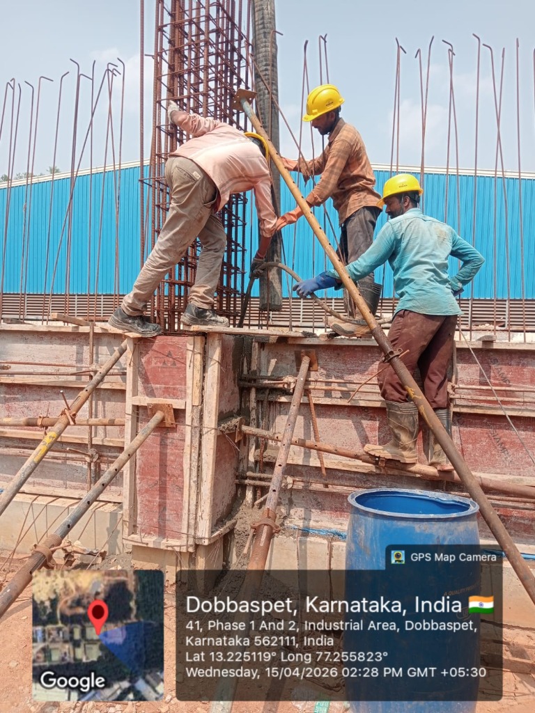Construction workers vibrating concrete for column and 12-inch RC wall shuttering at Dobbaspet site